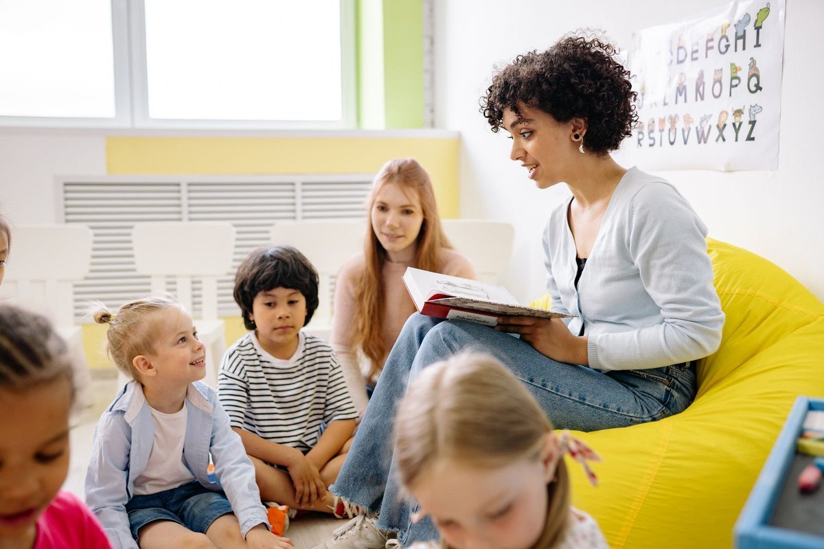 Teacher reading a book to preschoolers seated on the floor in a bright classroom